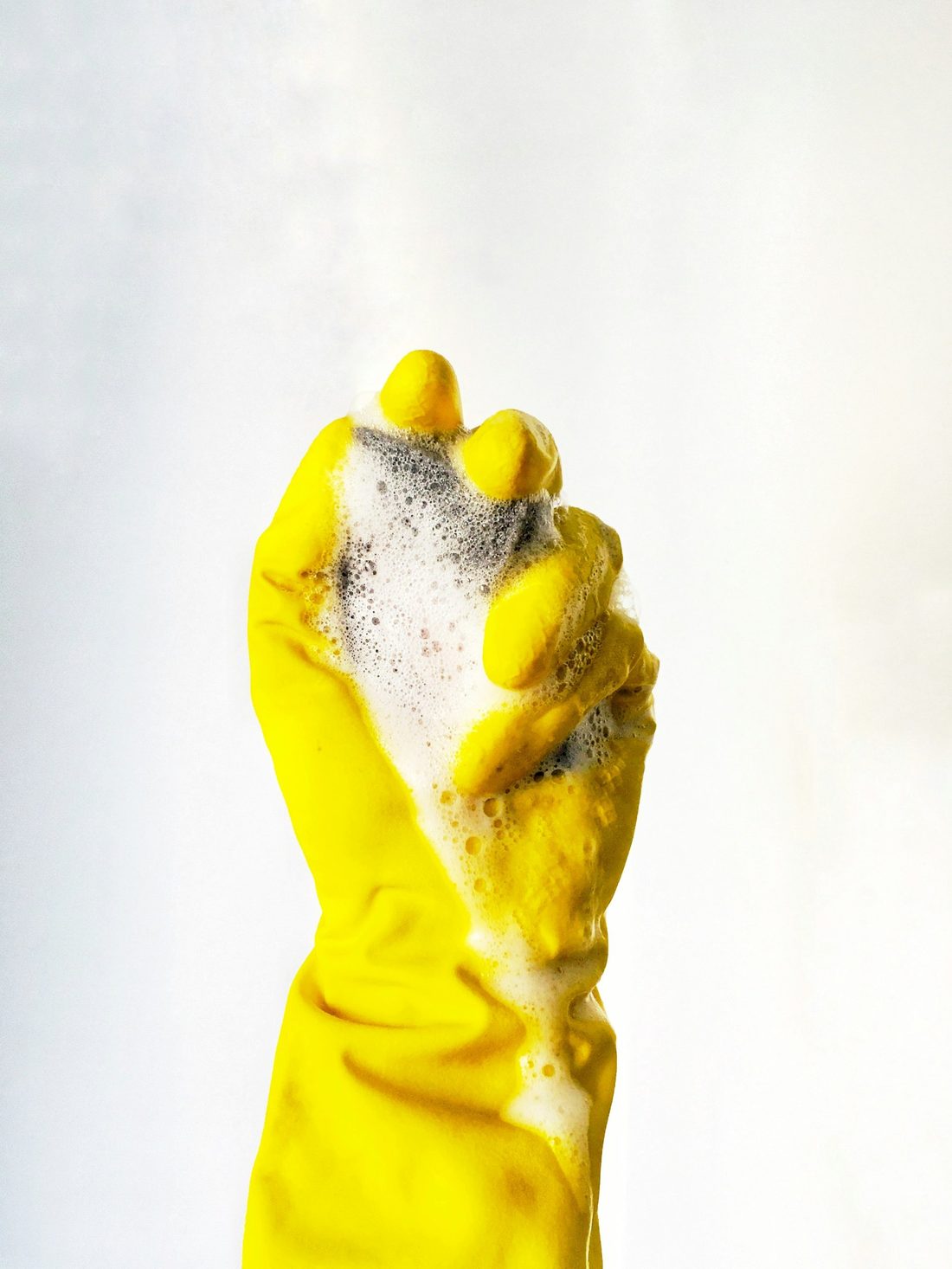 Yellow cleaning glove covered in soap foam