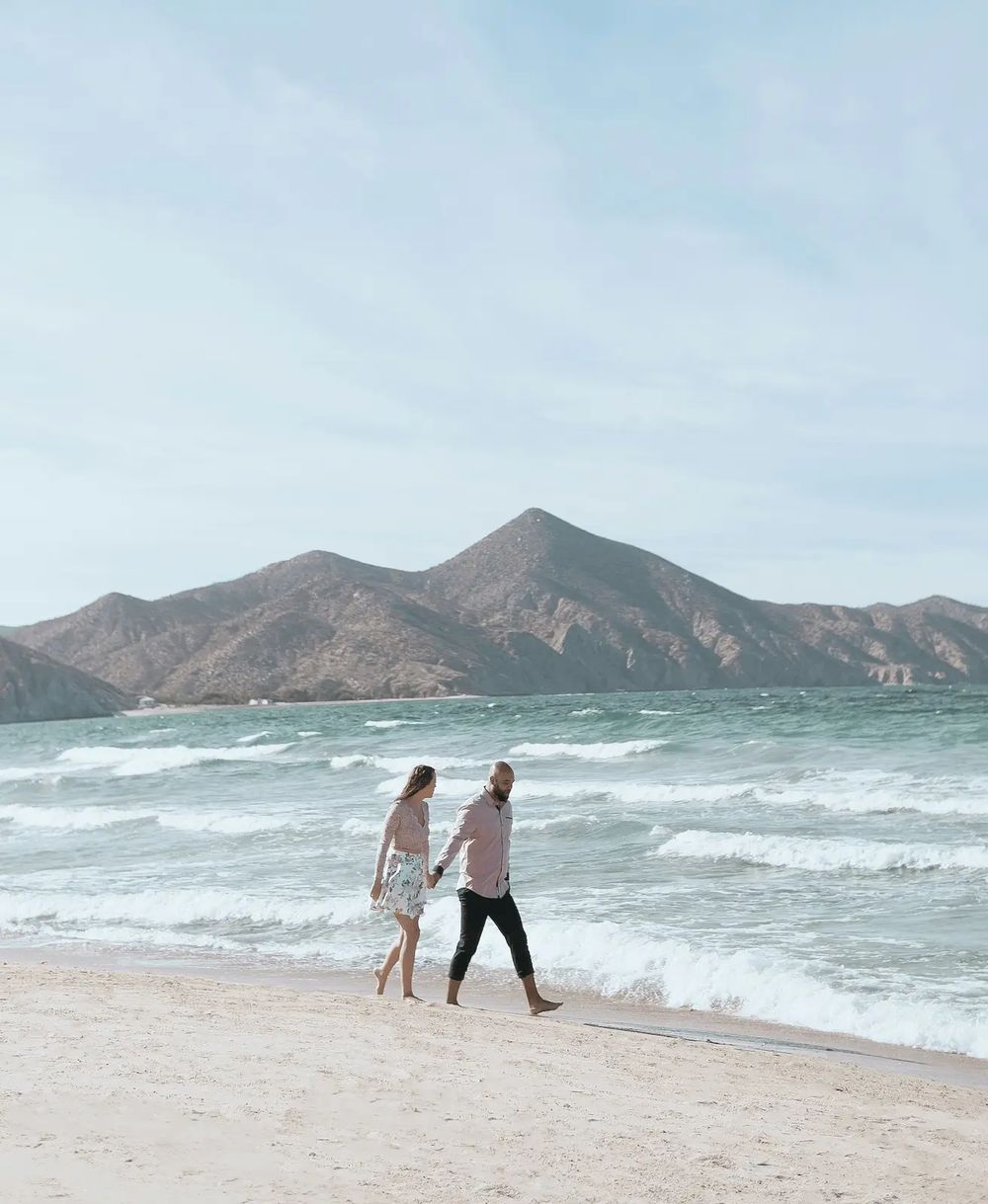 Cindy and Thom walking hand in hand along the shore